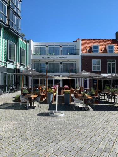 een binnenplaats met tafels, stoelen en parasols bij Stadshotel Vlissingen in Vlissingen