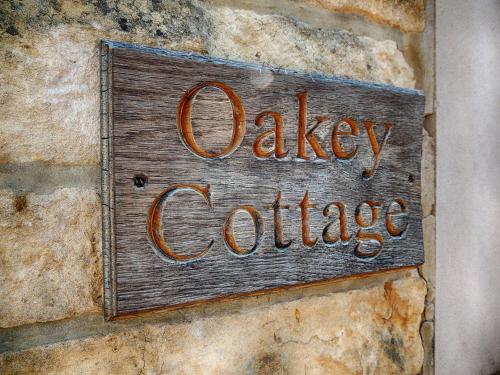 un cartello sul lato di un muro di pietra di Oakey Cottage a Bourton on the Water