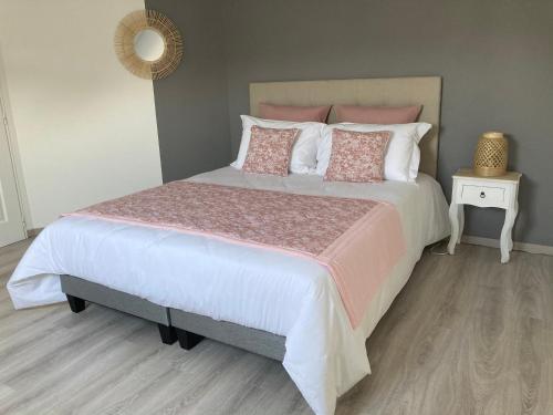 une chambre avec un grand lit avec des oreillers roses et blancs dans l'établissement Le chemin de la Loire, à Amboise