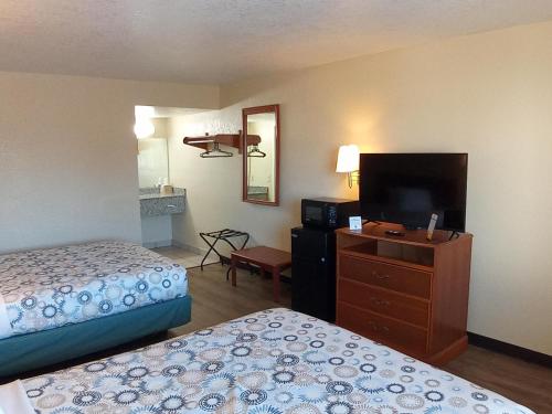 ein Hotelzimmer mit zwei Betten und einem Flachbildfernseher in der Unterkunft Hole Inn the Wall Hotel - Fort Walton Beach - Sunset Plaza - nearby Beaches & Hurlburt in Fort Walton Beach