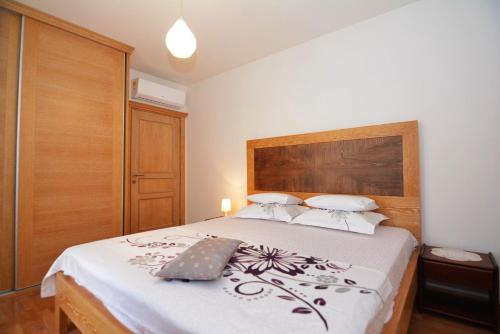 a bedroom with a bed with a wooden headboard at Apartments Olive in Kotor