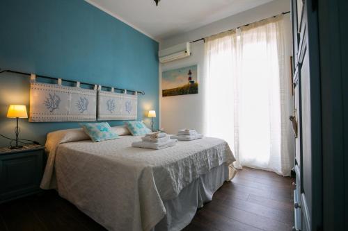 een slaapkamer met een bed met blauwe muren en een raam bij S'Arena Dorada Deluxe Apartment in Alghero