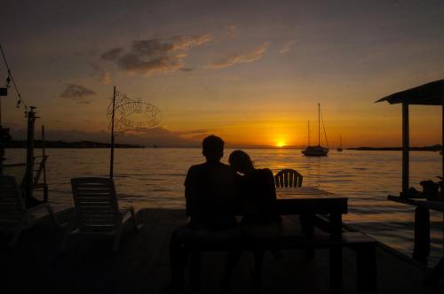 a man and woman sitting at a table watching the sunset at Saigon Bay Bed & Breakfast in Bocas del Toro