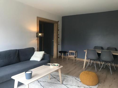 un salon avec un canapé bleu et une table dans l'établissement Appartement centre Barcelonnette, à Barcelonnette