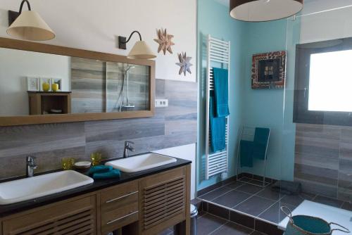 une salle de bain avec deux lavabos et un grand miroir dans l'établissement Chambres d'hôtes Les Baumes, à Saint-Quentin-la-Poterie