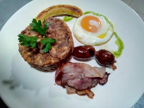 a white plate of food with an egg and meat at Techas City Center Luxurious Suite in Praia