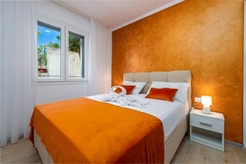 a bedroom with a bed with an orange wall at Apartment Tonka in Cavtat