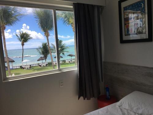 a bedroom with a window with a view of the beach at Praia dos Carneiros apart beira-mar in Tamandaré