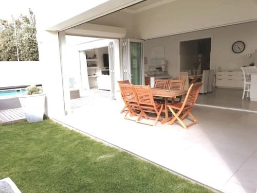 una casa con patio con mesa de madera y sillas en A home for the ultimate West Coast beach holiday en St Helena Bay