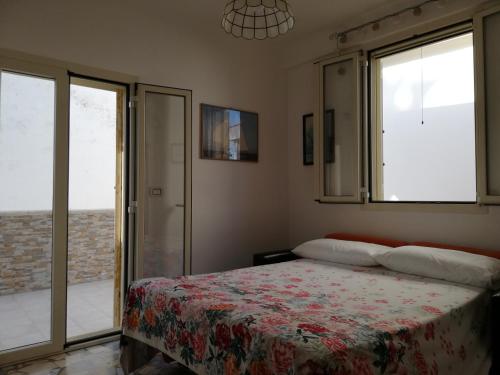 Schlafzimmer mit einem Bett und Glasschiebetüren in der Unterkunft GIADA MARIA SOLE HOUSE in Pulsano