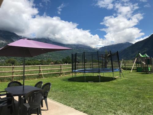 une table et des chaises avec un parasol et un trampoline dans l'établissement maisonnette entre lac de Passy et montagnes, à Domancy