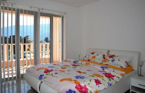 a white bedroom with a bed with flowers on it at Montesun Residence in Herceg-Novi