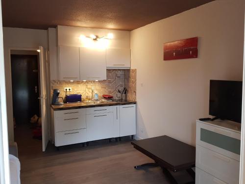 une petite cuisine avec des placards blancs et une télévision dans l'établissement Studio confortable au calme proche du port et de la plage grande terrasse et parking résidence le Grand Large, à Saint-Mandrier-sur-Mer