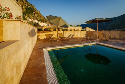 a swimming pool with chairs and an umbrella on a patio at Apartments Casa Delone in Kotor