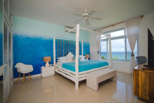 a bedroom with a white canopy bed with a view of the ocean at Ocho Rios Penthouse at Whispering Seas in Ocho Rios