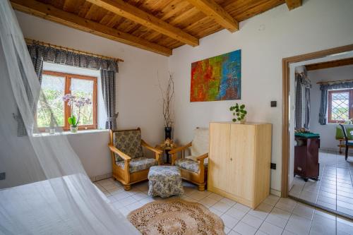 a living room with a bed and a chair at Hillside Vendégház a Szent György-hegyen in Raposka