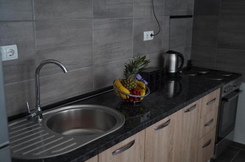 a kitchen counter with a sink and a bowl of fruit at apartman Vidović in Livno