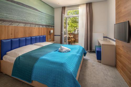 a bedroom with a blue bed with a cat laying on it at Hotel Solero in Siófok