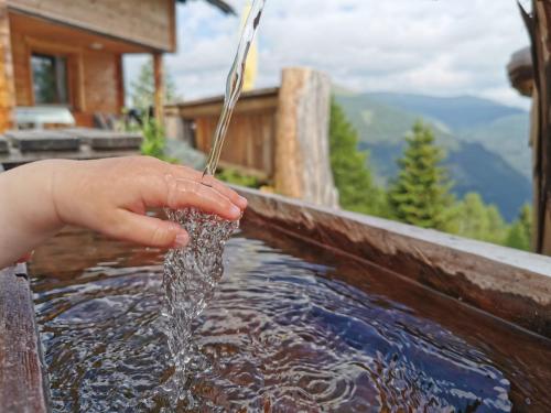 a child is drinking water from a fountain at Almhütte Kristabauer in Predlitz