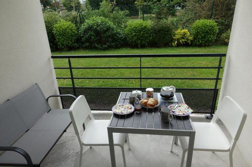 d'une table et de chaises avec de la nourriture sur le balcon. dans l'établissement L'Océanide - Appartement avec balcon-terrasse et parking privé, à Pont-lʼAbbé
