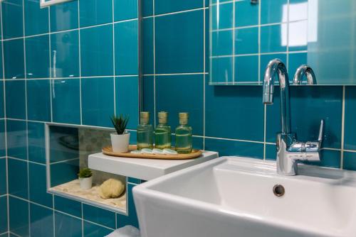 La salle de bains est pourvue d'un lavabo et d'un mur carrelé bleu. dans l'établissement Blue Horizon, à Paleóchora