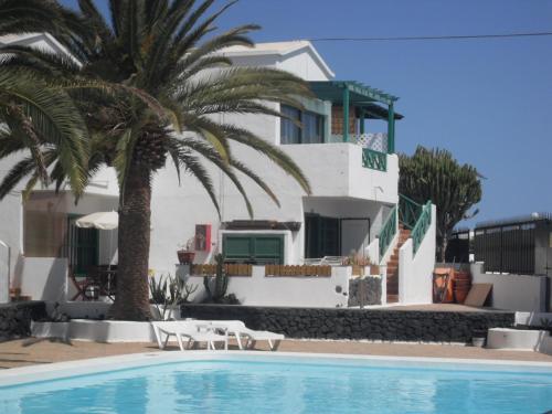 a house with palm trees and a swimming pool at Irene Apartment in Puerto del Carmen