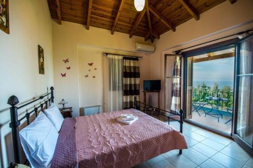 una camera da letto con un letto con copriletto rosa e un balcone di Kelly's Villa in Stoupa a Neokhórion
