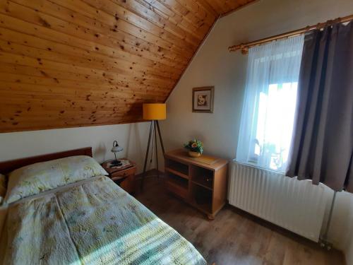 a bedroom with a bed and a wooden ceiling at Anna vendégház in Tihany