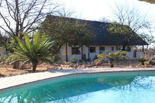 a house and a swimming pool in front of a house at Thula Private Lodge in Phalaborwa