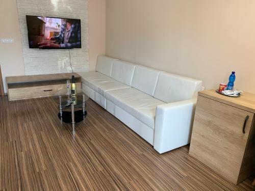 a white couch in a room with a tv on a wall at ELTAKO penzion in Karlovy Vary