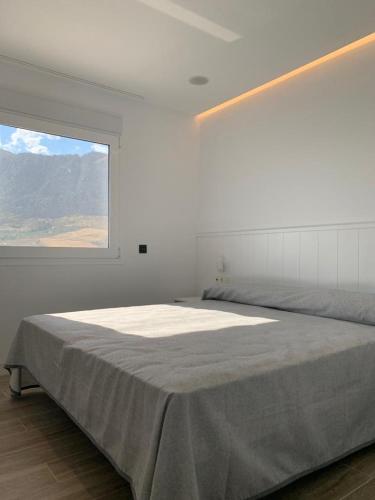 a white bedroom with a large bed with a window at Casa Raquel,caminito del Rey in Valle de Abdalagís