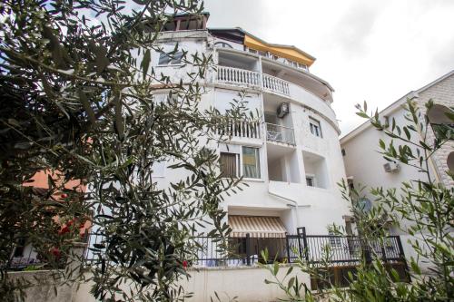 a tall white building with a balcony at Dom B Apartments in Budva