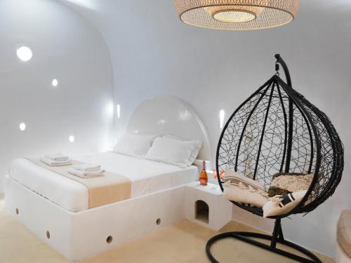 a bedroom with a bed with a swing and a chair at Secret Gem Suites in Oia