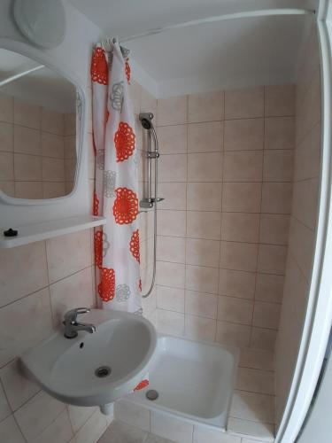 a bathroom with a sink and a shower curtain at Noclegi, pokoje na Piaskach in Krynica Morska
