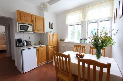 a kitchen with a table with a vase of flowers on it at Penzion Jelen Vranov nad Dyjí in Vranov nad Dyjí