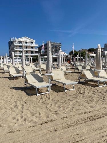 a row of lounge chairs on the beach at Hotel Ivana in Lido di Jesolo