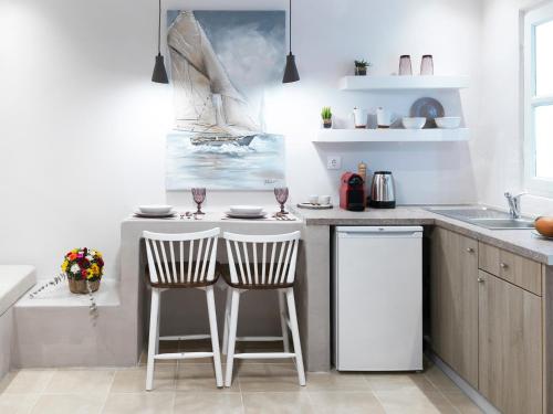 a kitchen with two bar stools and a sink at Secret Gem Suites in Oia