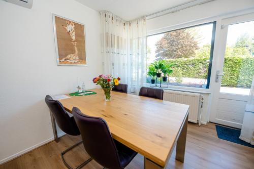 a dining room with a wooden table and a large window at B&B Het Station bij Snowworld GaiaZoo en Mondo Verde in Landgraaf