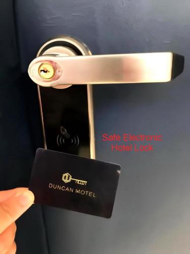 a person holding a door handle with a hotel label at Duncan Motel in Duncan