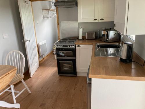 a small kitchen with a stove and a table at Kabin in the woods with Hot Tub in Llandybie