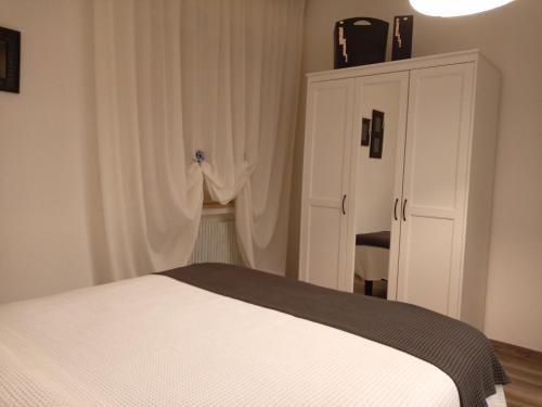 a bedroom with a white bed and a cabinet at La Cjase di Pieri e Vilme in Udine