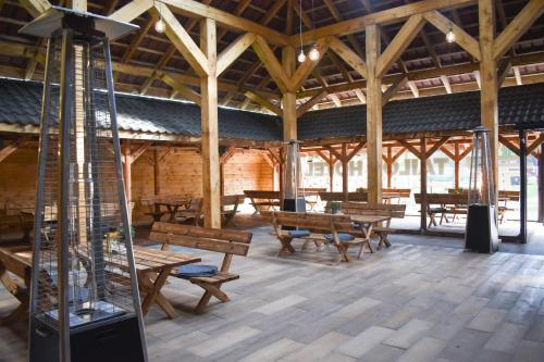 a large wooden building with wooden benches and tables at Tailor Hotel Sport & Conference in Morąg