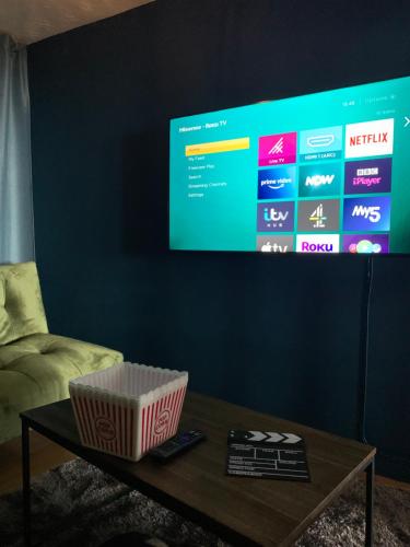 ein Wohnzimmer mit einem Tisch und einem TV an der Wand in der Unterkunft Stunning 3 bed seafront mansion building sleeps 6 adults or 8 with kids in Portrush