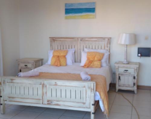 een slaapkamer met een wit bed met oranje kussens bij Vila Sol - Self Catering in Vila Praia Do Bilene