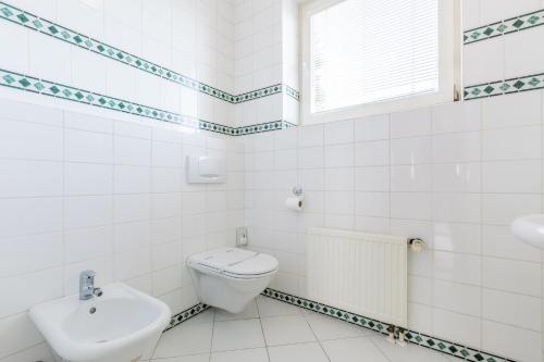 a white bathroom with a toilet and a sink at Hotel U Rytíře in Mělník