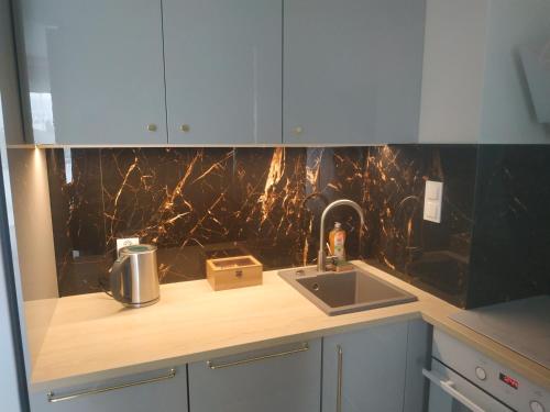 a kitchen with a counter with a sink and a counter at Perła Apartament Mińsk in Mińsk Mazowiecki