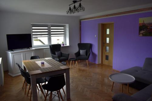 ein Wohnzimmer mit lilafarbenen Wänden sowie einem Tisch und Stühlen in der Unterkunft PENSION NA BORŮVKOVÉM VRŠKU in Bujanov