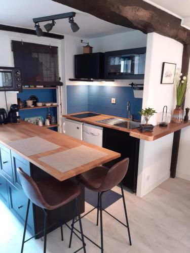 cocina con mesa de madera y armarios azules en Appartement Haute Ville meublé avec cour privative, en Granville