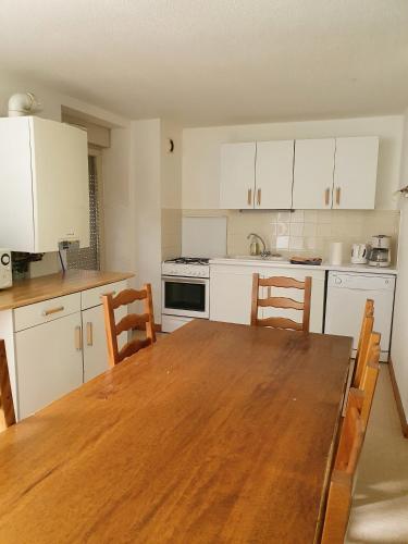 une cuisine avec une table en bois et des armoires blanches dans l'établissement Gîte du Moulin, à Les Planches-près-Arbois