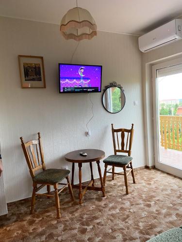a dining room with a table and two chairs and a tv at Piroska Apartment in Zalakaros
